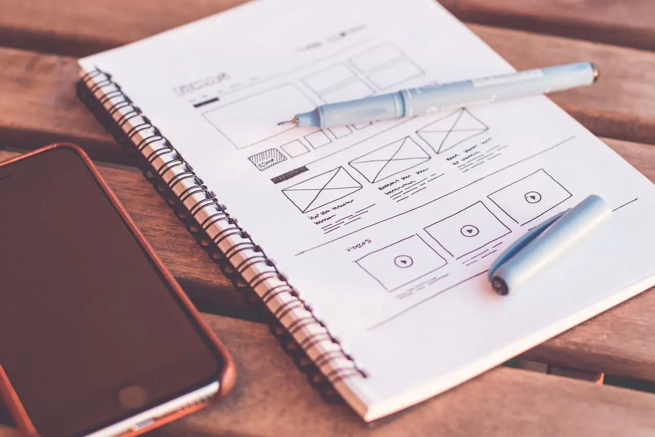“notepad with the wireframe of a website hand drawn on it”